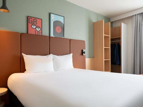 a bedroom with a large bed with white sheets at ibis Paris Gare de Lyon Ledru Rollin in Paris