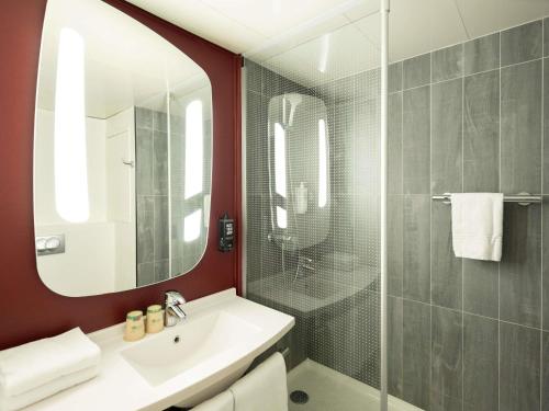 a bathroom with a sink and a shower with a mirror at ibis Paris Gare de Lyon Ledru Rollin in Paris