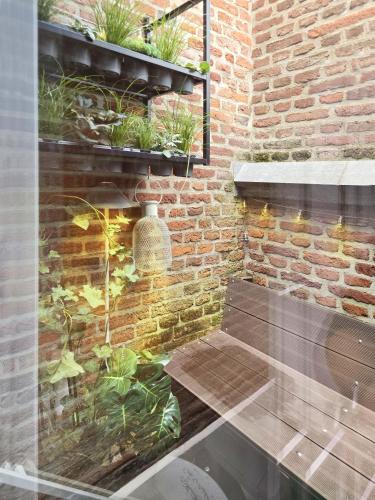 a room with a brick wall with plants at Loft Mons Centre 5 in Mons