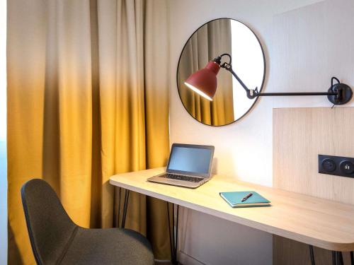 a laptop computer sitting on a desk with a mirror at Mercure Cavaillon in Cavaillon