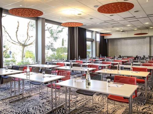 a dining room with tables and red chairs at Mercure Cavaillon in Cavaillon