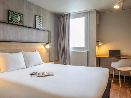 a hotel room with a bed with a book on it at ibis Paris Gennevilliers in Gennevilliers