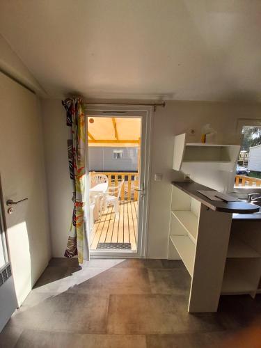a small kitchen with a door to a patio at Escale Nature - Bungalow F14 pour 4 au camping Le Ried in Boofzheim