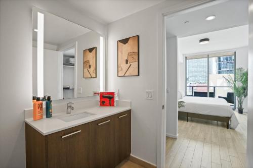 a bathroom with a sink and a mirror and a bed at Cadenza Miami - Luxury Residences in Miami