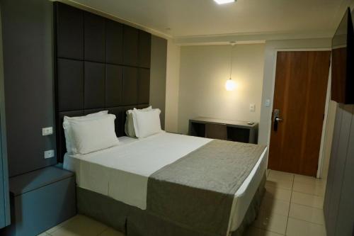 a bedroom with a large bed with white pillows at Hotel Village Premium Caruaru in Caruaru