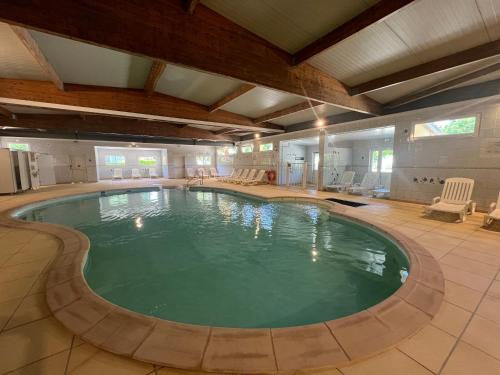 a large swimming pool in a large room with chairs at Escale Nature - Bungalow F14 pour 4 au camping Le Ried in Boofzheim