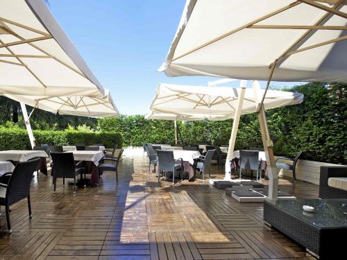 a patio with tables and chairs and umbrellas at Mercure Reggio Emilia Centro Astoria in Reggio Emilia