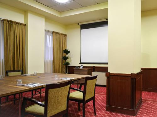 a conference room with a table and a projection screen at Mercure Reggio Emilia Centro Astoria in Reggio Emilia