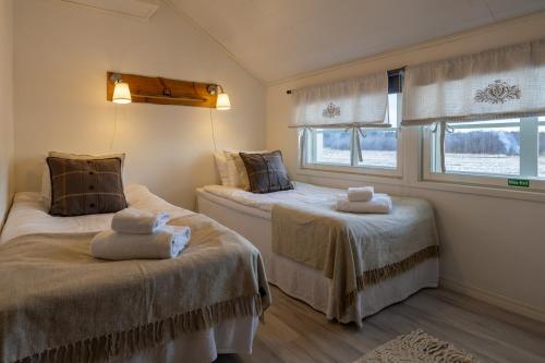 two beds in a room with two windows at Loimu Resort in Ylläsjärvi