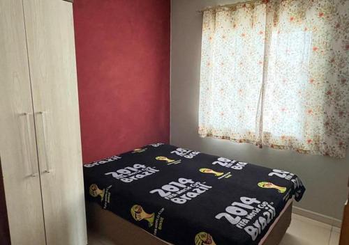 1 dormitorio con 1 cama con edredón negro y ventana en Residencial Day off, en Guaratuba