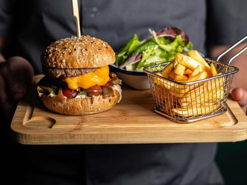 eine Person mit einem Tablett mit einem Sandwich und Pommes frites in der Unterkunft Novotel Paris Pont De Sevres in Sèvres