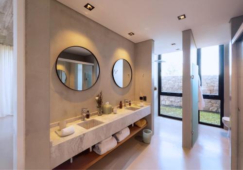 a bathroom with two sinks and two mirrors at Posada Ayana - Adults Only in José Ignacio