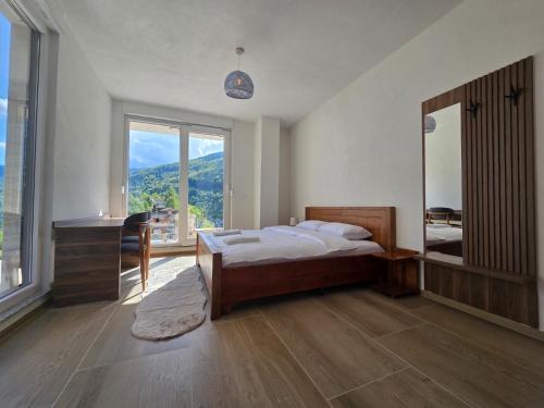 una camera da letto con un letto, una scrivania e una grande finestra di Belle Resort a Deçan
