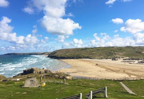 a view of a beach with a bench and the ocean at Inn For All Seasons in Redruth