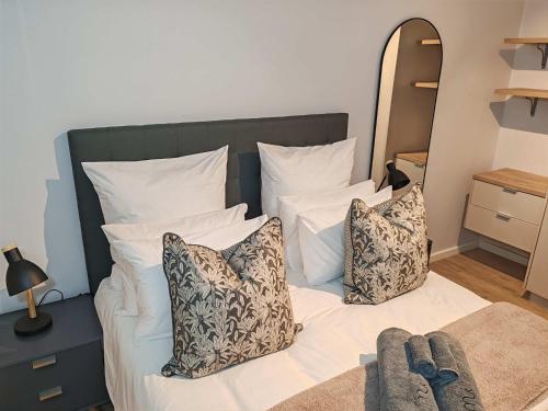 a bedroom with a bed with white pillows and a mirror at Wavescapes Tides Stay in Muizenberg