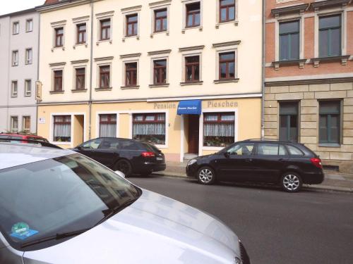 three cars parked on a street in front of a building at Pension Pieschen Dresden in Dresden