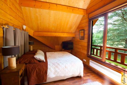 um quarto num chalé de madeira com uma cama e uma janela em Chambres d'Hôtes Le Chalet em Condat-sur-Vienne