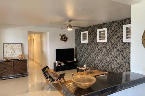 a living room with a table and a tv at Villa Le Nid des Colibris in Saint-Charles