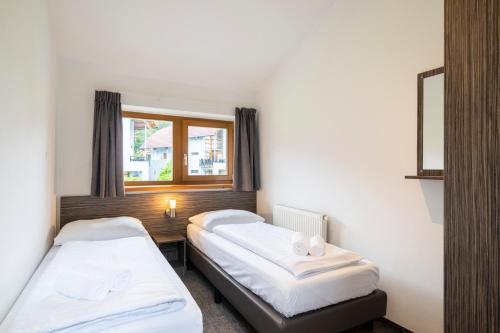 two beds in a room with a window at Landal Marina Lipno in Lipno nad Vltavou