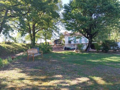 a bench sitting in the grass in front of a house at La Chesnaie in Bonnes