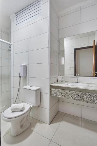 a white bathroom with a toilet and a sink at Hotel Nacional Inn Piracicaba in Piracicaba