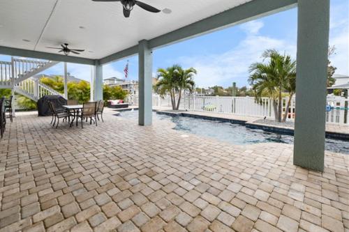 a patio with a table and chairs and a pool at Spacious Home With Heated Pool! Sleeps 15! Billiard table! in Hernando Beach