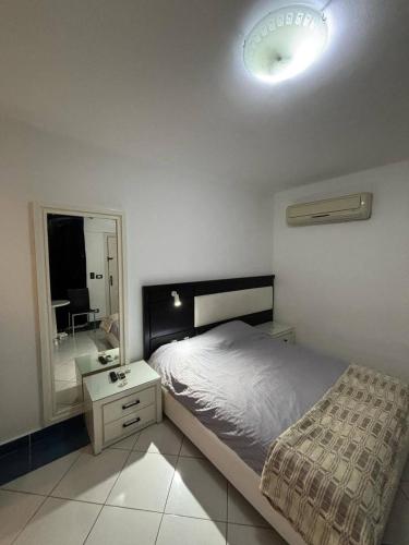 a bedroom with a bed and a nightstand and a mirror at Studio 102-108 in Banī Ghālib