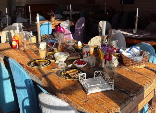 Una mesa de madera con comida y velas encima. en Bäckdalens Bed and Breakfast & Café, en Båstad
