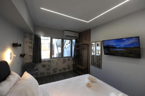 ein Schlafzimmer mit einem Bett und einem Fernseher an der Wand in der Unterkunft Cozy Loft Monastiraki in Athen
