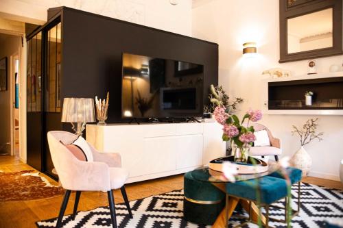 ein Wohnzimmer mit Fernseher und Tisch und Stühlen in der Unterkunft Pretty house - near botanical garden in Bordeaux