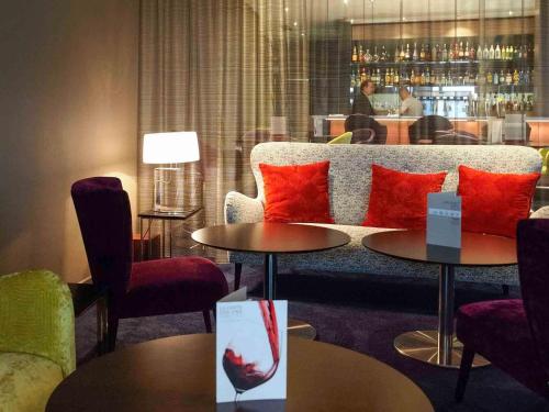 a living room with red pillows on a couch and tables at Mercure Nantes Centre Grand Hotel in Nantes