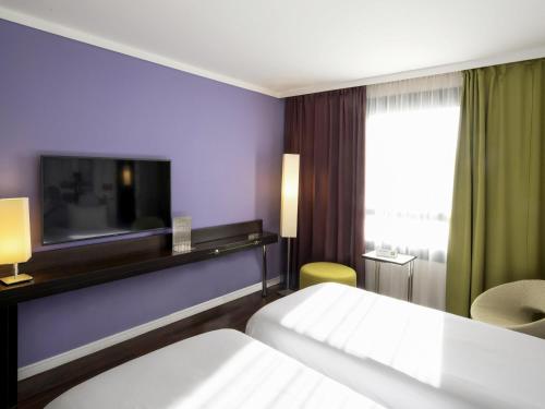 a hotel room with a bed and a flat screen tv at ibis Styles Evry Courcouronnes Hotel and Events in Evry-Courcouronnes