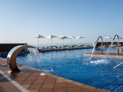 a swimming pool with fountains and umbrellas at Mercure Monte Igueldo in Donostia-San Sebastián