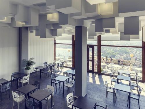 a restaurant with tables and chairs and a large window at Mercure Monte Igueldo in Donostia-San Sebastián