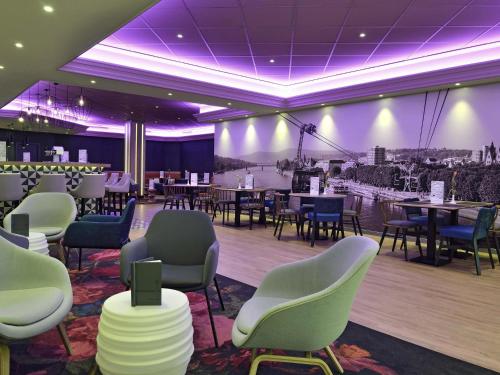 a dining room with tables and chairs and purple lighting at Mercure Hotel Koblenz in Koblenz