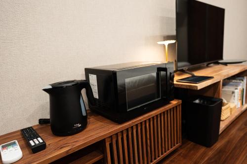 a microwave sitting on top of a wooden shelf at UNZIPPER KUMAMOTO - Private Sauna Stay - in Kumamoto