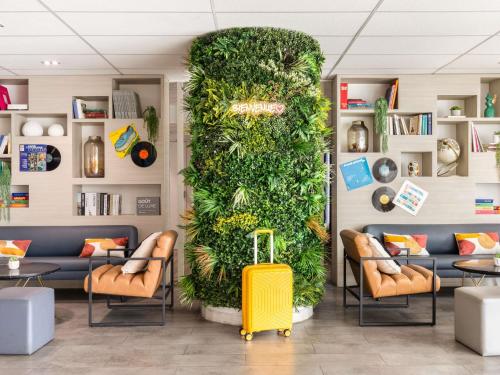 a large green wall in a waiting room with a yellow suitcase at ibis Paris Porte de Montreuil in Paris