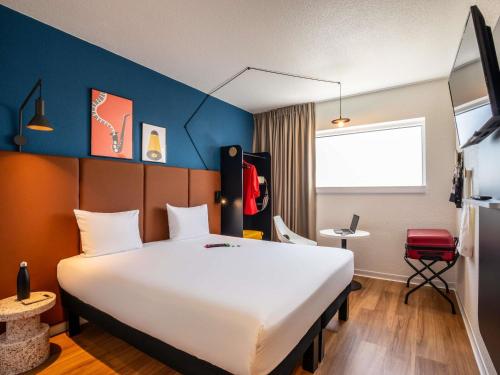 a hotel room with a large white bed and a blue wall at ibis Paris Porte de Montreuil in Paris