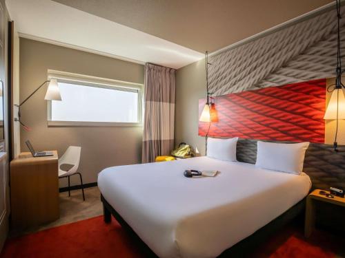 a hotel room with a large white bed and a desk at ibis Paris Porte de Montreuil in Paris