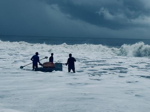 three men in the ocean with a boat in the water at Coconut Bay Marari in Mararikulam