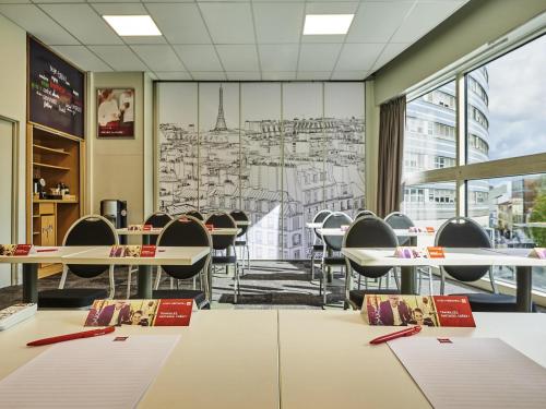 a conference room with tables and chairs and a large window at ibis Paris Porte de Montreuil in Paris