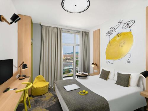 a hotel room with a large bed and a desk at Ibis Styles Budapest City in Budapest