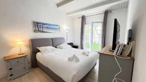 a bedroom with a bed with a television and a desk at Superbe villa avec piscine chauffée in Sainte-Marie-de-Ré