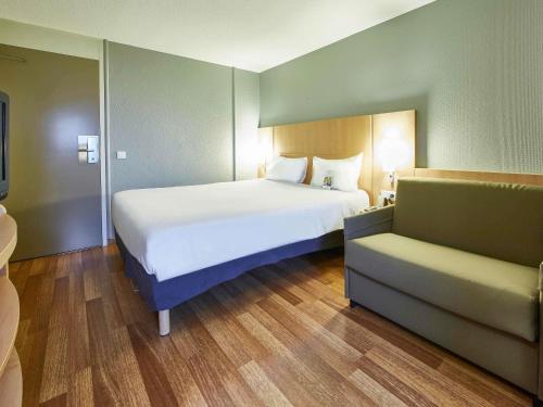 a bedroom with a large white bed and a couch at ibis Haguenau Strasbourg Nord in Haguenau