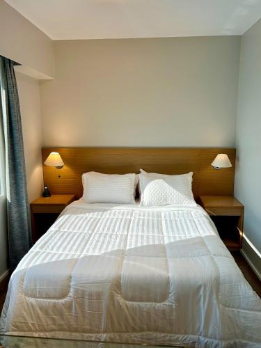 a bedroom with a large white bed with two lamps at Ao lado da Paulista e metrô lazer completo com estac in Sao Paulo