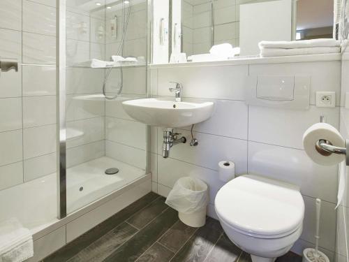 a white bathroom with a toilet and a sink at ibis Haguenau Strasbourg Nord in Haguenau