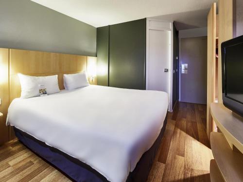 a large white bed in a room with a tv at ibis Haguenau Strasbourg Nord in Haguenau