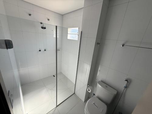 a white bathroom with a shower and a toilet at Hotel Mato Grosso Inn in Cuiabá