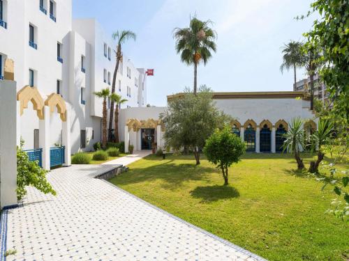 einen Innenhof eines Gebäudes mit Rasen und Palmen in der Unterkunft Ibis Fes in Fès