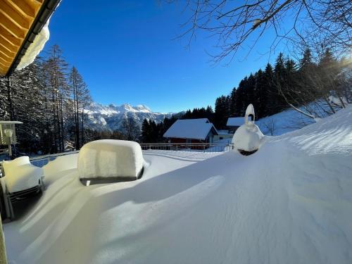 a snow covered yard with two snow covered cars at Haus Heimetli - CharmingStay in Flumserberg